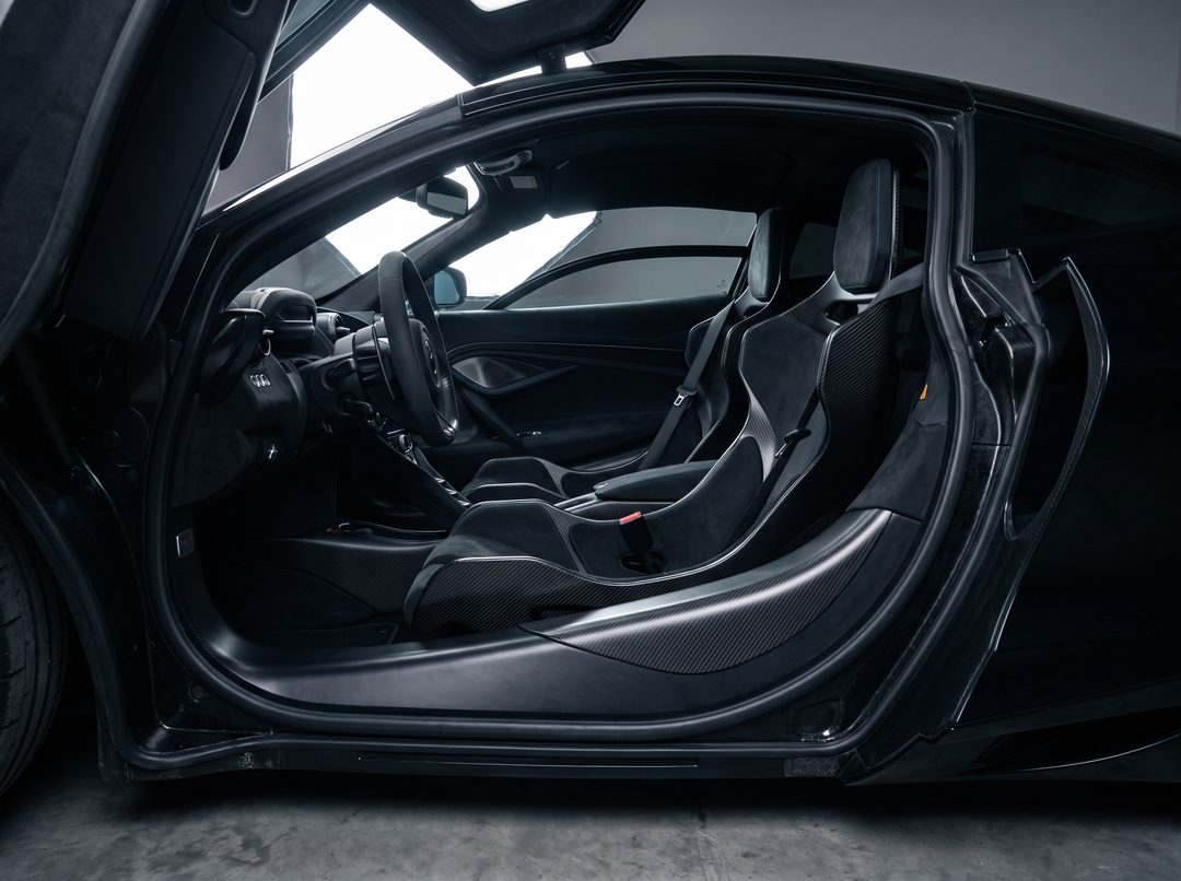 The cabin of a finished supercar build seen through the raised door, carbon sill and alcantara bucket seats